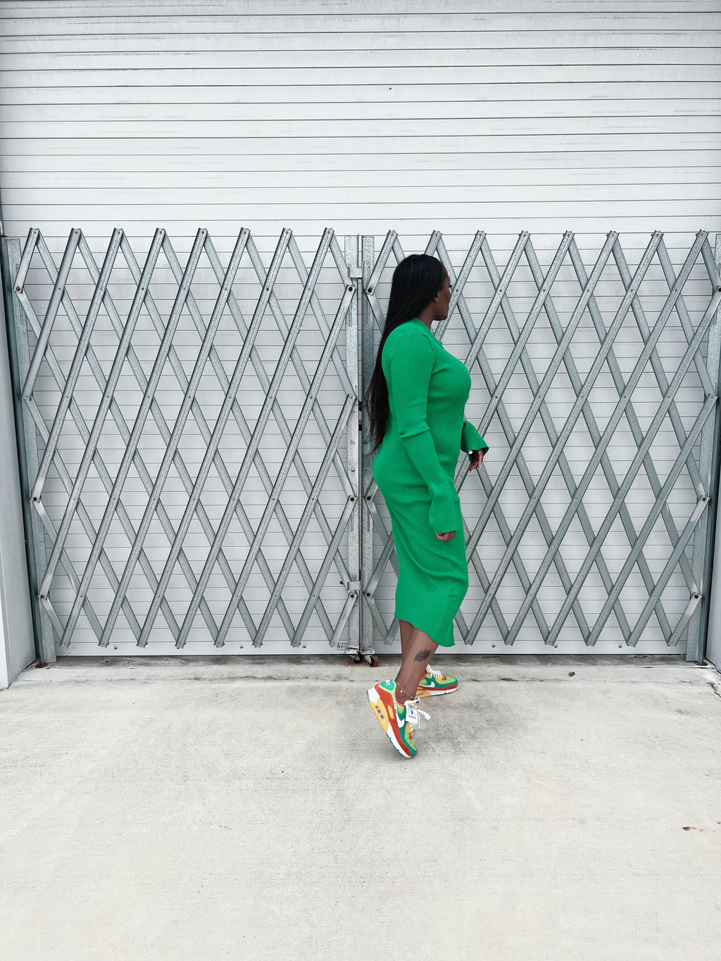 Back view of a green ribbed maxi dress with a tailored fit, long sleeves, and flowing bell cuffs